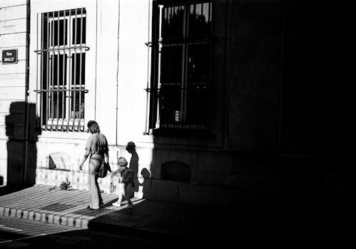 Black and white photo of a mother and child walking on Rue Bailly in Nancy, France.